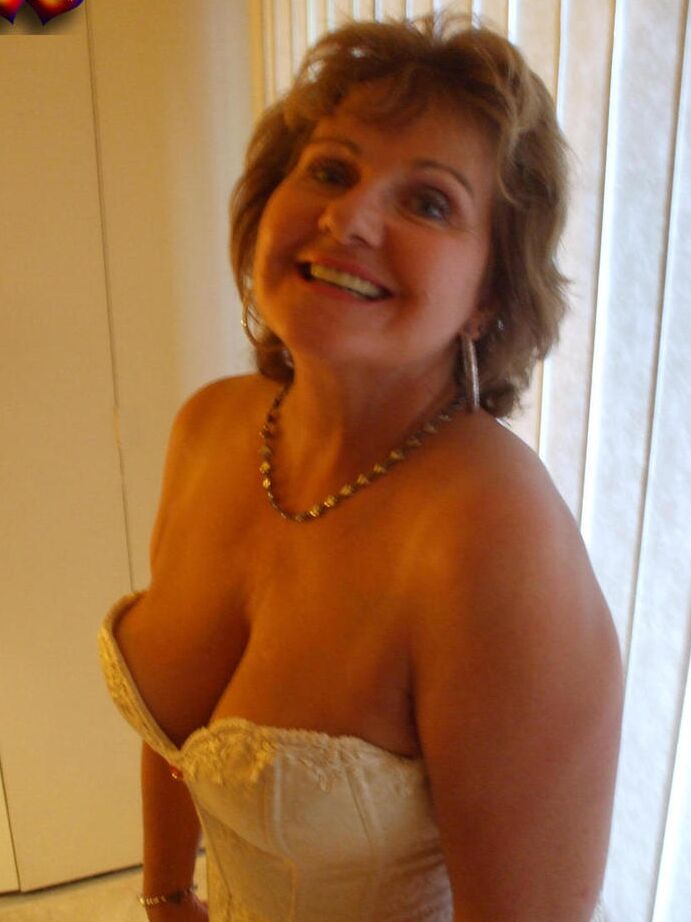 20P Busty Bliss mais velha e excitada em lingerie de cetim branco se curva para exibir sua bunda grande