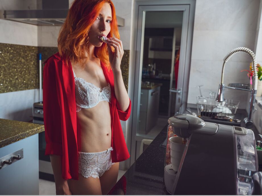 18P La joven pelirroja Elin Dane se desnuda totalmente en la cama con una bebida caliente