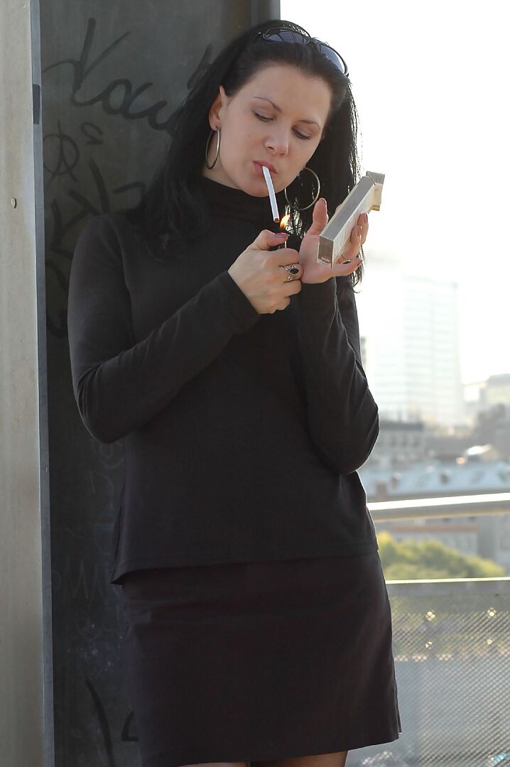 16P Fully clothed brunette lights up a cigarette with her sunglasses atop her head