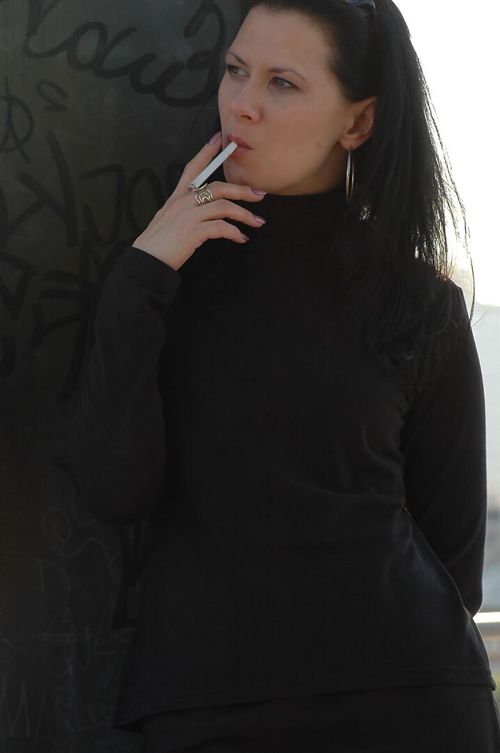 16P Fully clothed brunette lights up a cigarette with her sunglasses atop her head