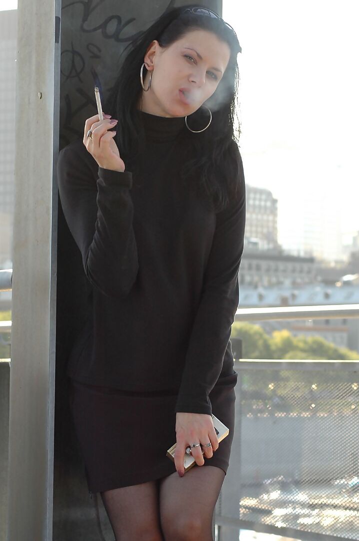 16P Fully clothed brunette lights up a cigarette with her sunglasses atop her head