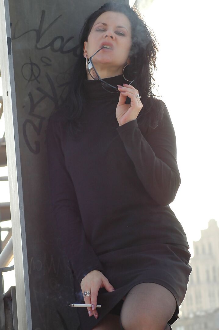 16P Fully clothed brunette lights up a cigarette with her sunglasses atop her head