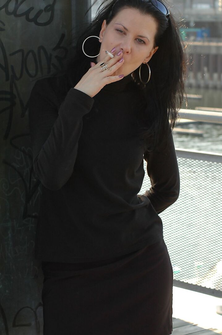 16P Fully clothed brunette lights up a cigarette with her sunglasses atop her head