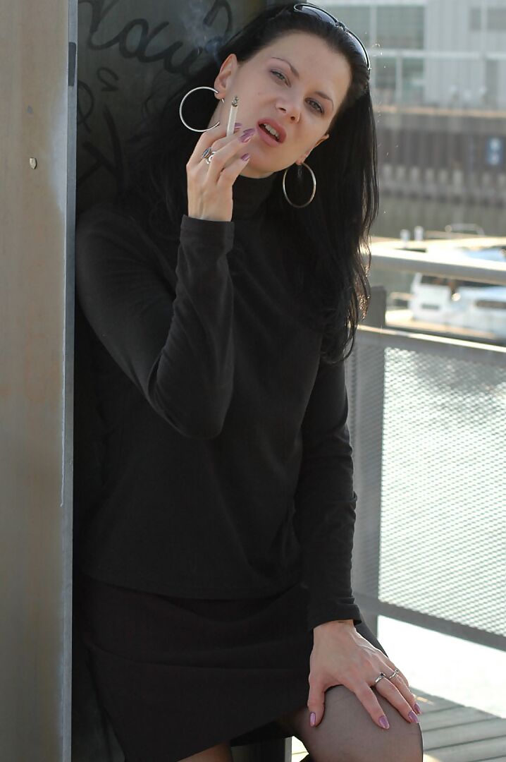 16P Fully clothed brunette lights up a cigarette with her sunglasses atop her head