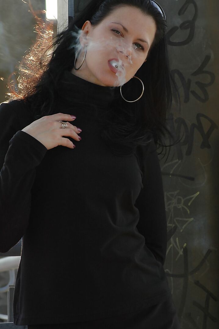 16P Fully clothed brunette lights up a cigarette with her sunglasses atop her head
