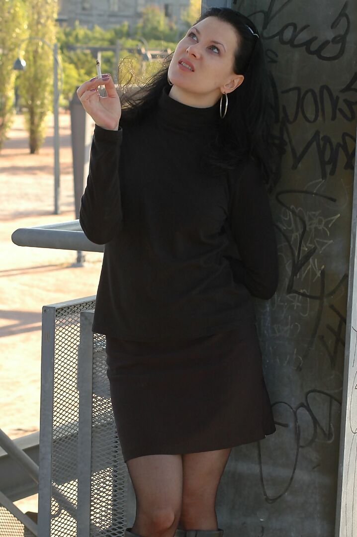 16P Fully clothed brunette lights up a cigarette with her sunglasses atop her head