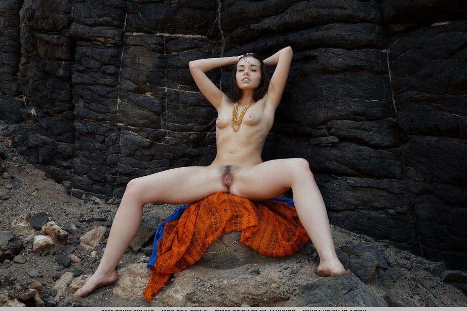 18P La joven morena Keira Blue posa completamente desnuda contra una pared de roca