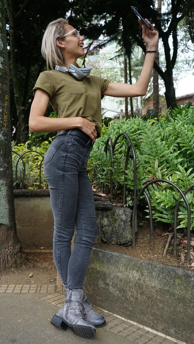 16P Verónica Leal posando sobre toda su capucha con camisa verde y jeans ajustados