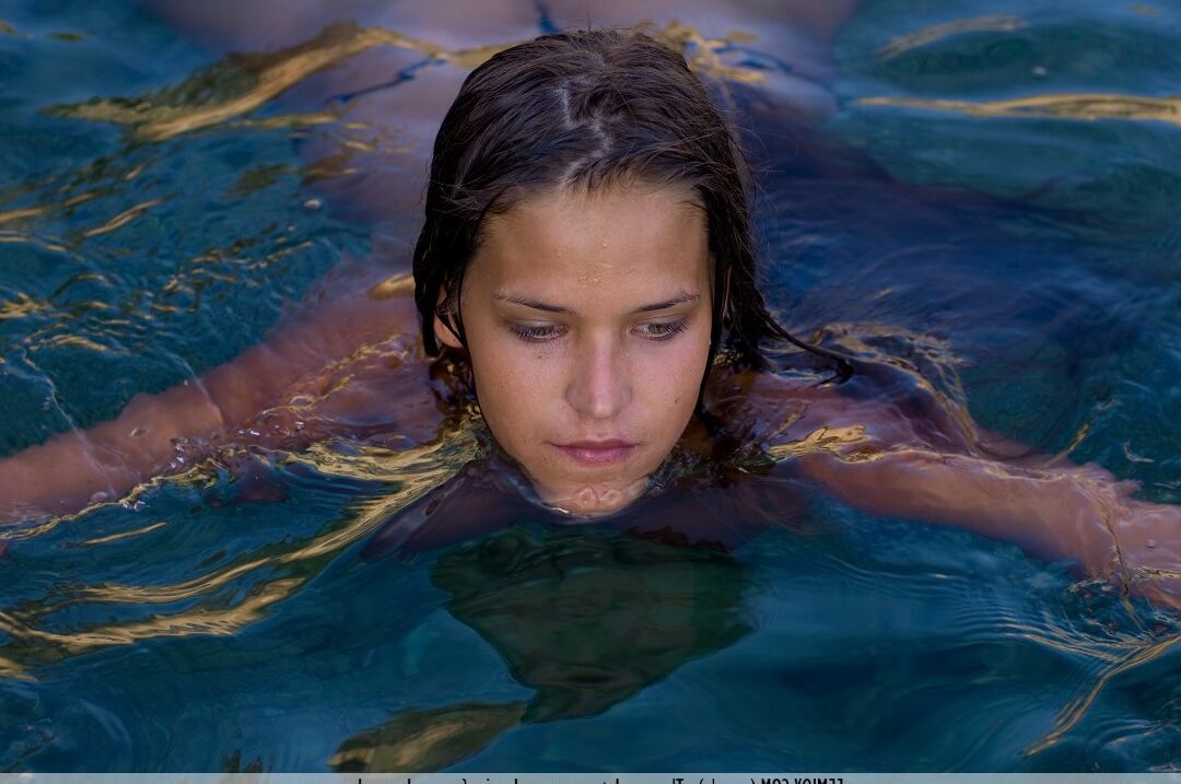 16P Simona, une adolescente nue, s'enfonce jusqu'au cou dans une eau cristalline
