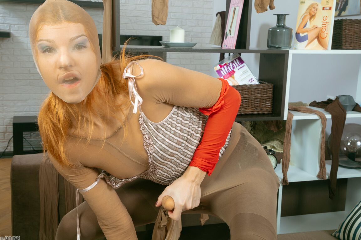 16P Redheaded girl encases herself in pantyhose while wearing a strapon cock