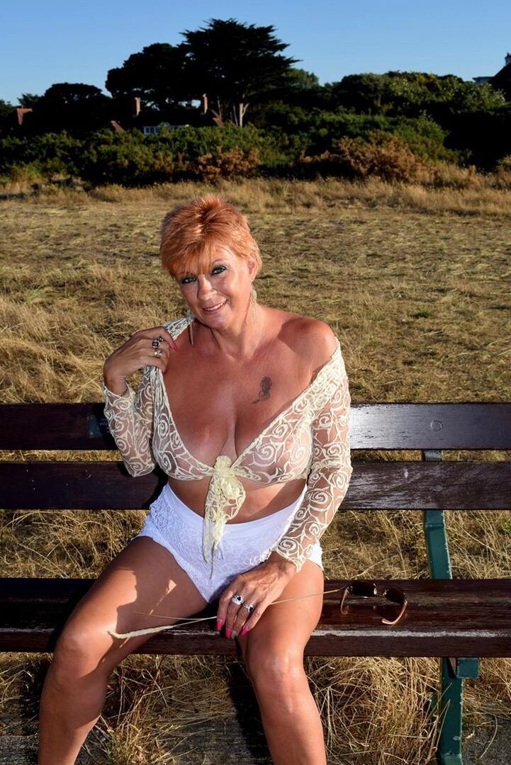 16P Mature redhead Dimonty exposes her sagging tits on a bench down by the sea
