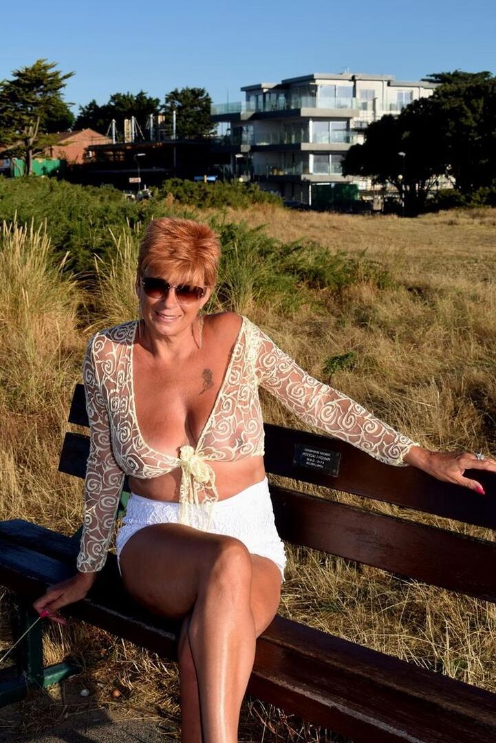 16P Mature redhead Dimonty exposes her sagging tits on a bench down by the sea