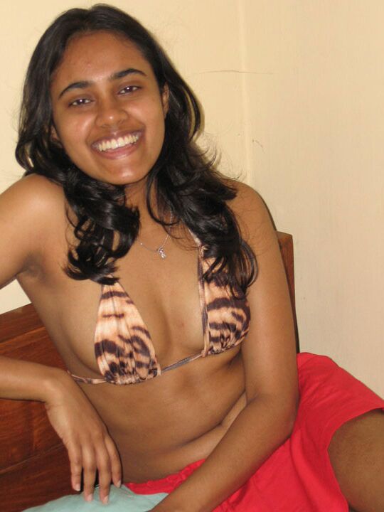 10P Indian girl with a nice smile shows her breasts on top of a bed