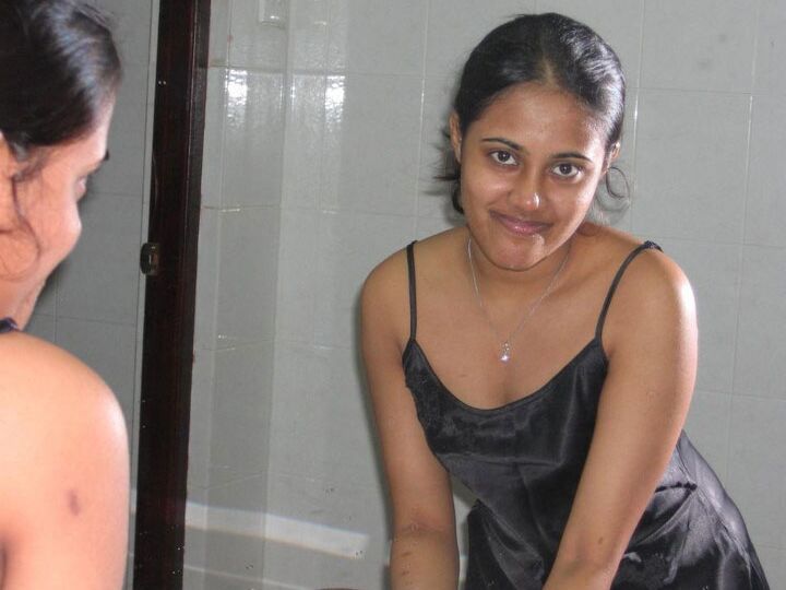 10P Indian girl with a nice smile shows her breasts on top of a bed