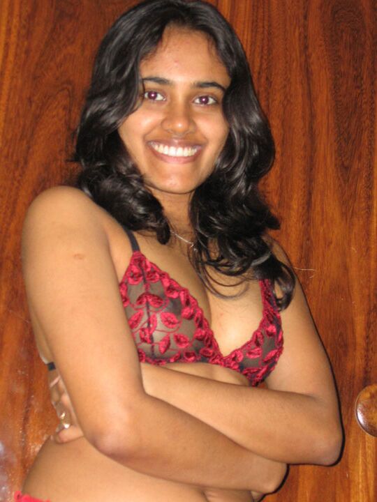 10P Indian girl with a nice smile shows her breasts on top of a bed