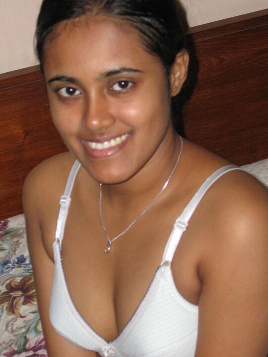 10P Indian girl with a nice smile shows her breasts on top of a bed