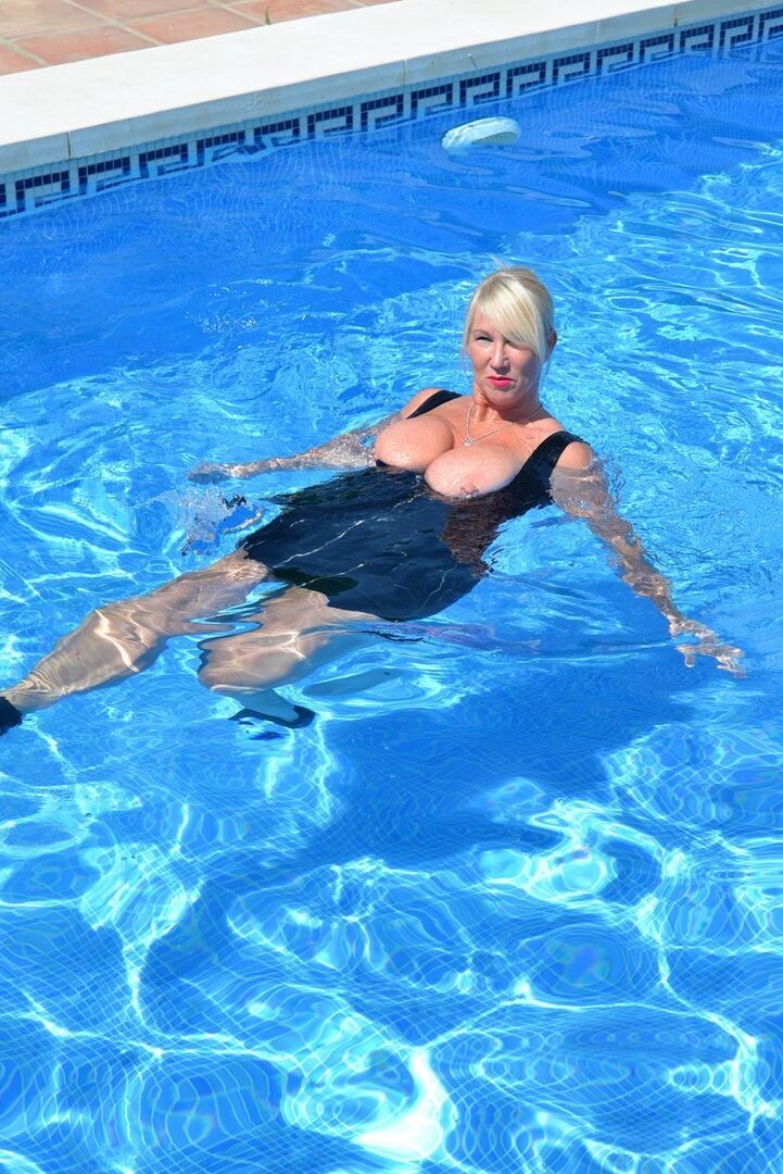 20P Thick blonde Melody displays her ample cleavage while fully clothed in a pool