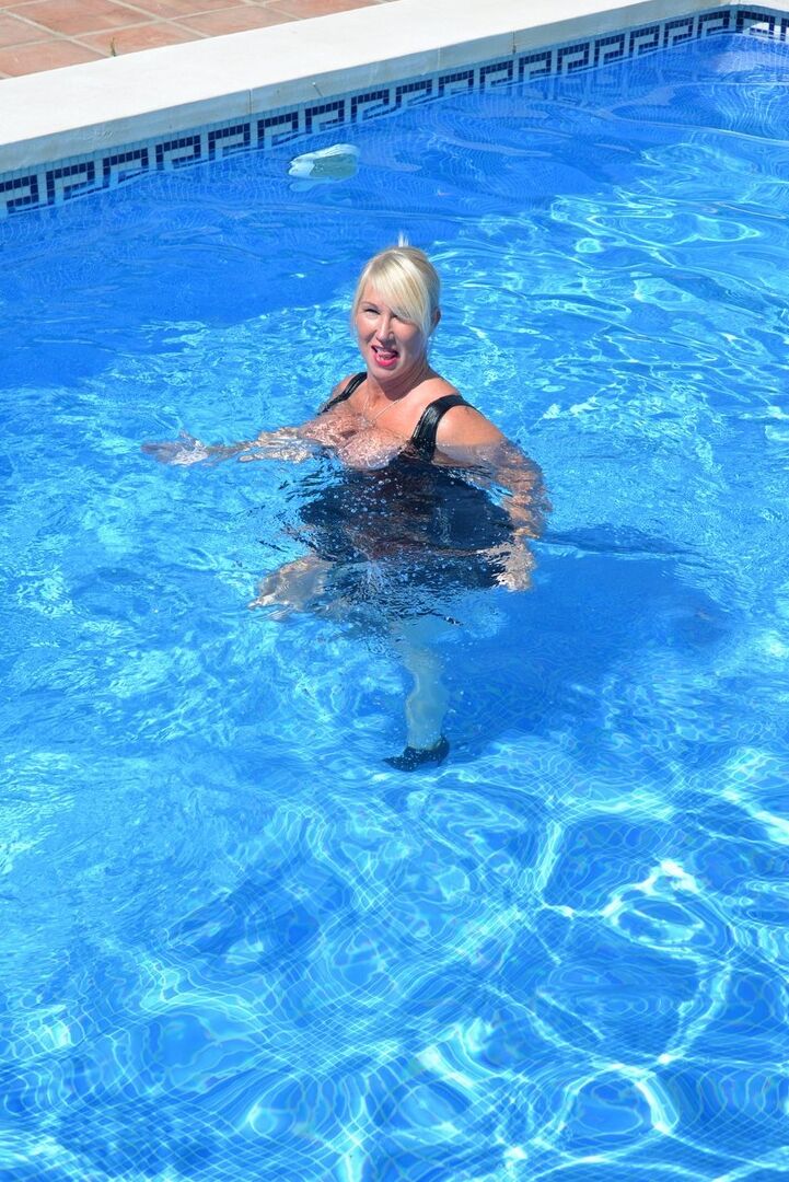 20P Thick blonde Melody displays her ample cleavage while fully clothed in a pool