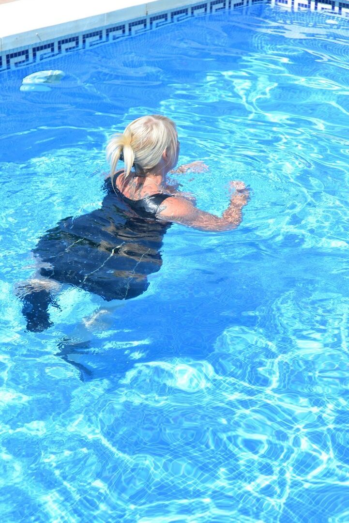 20P Thick blonde Melody displays her ample cleavage while fully clothed in a pool