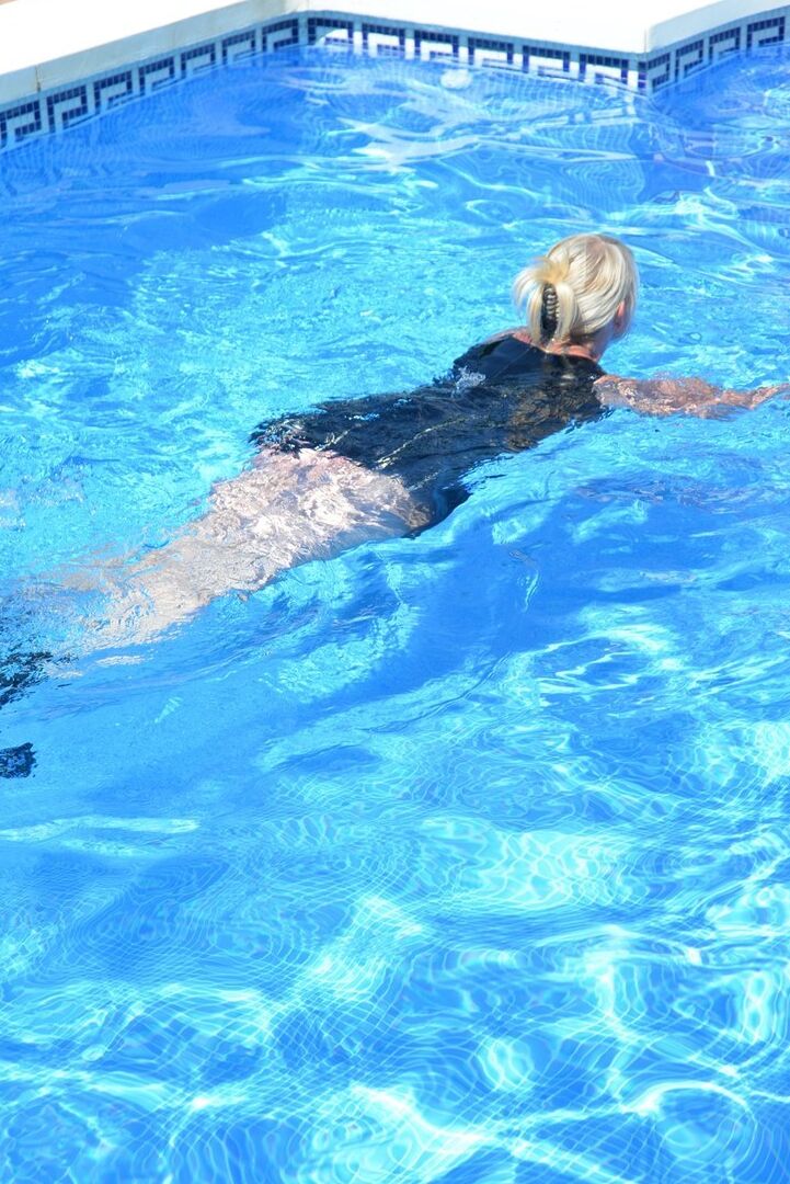 20P Thick blonde Melody displays her ample cleavage while fully clothed in a pool