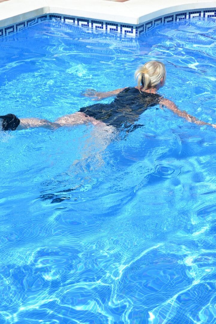 20P Thick blonde Melody displays her ample cleavage while fully clothed in a pool