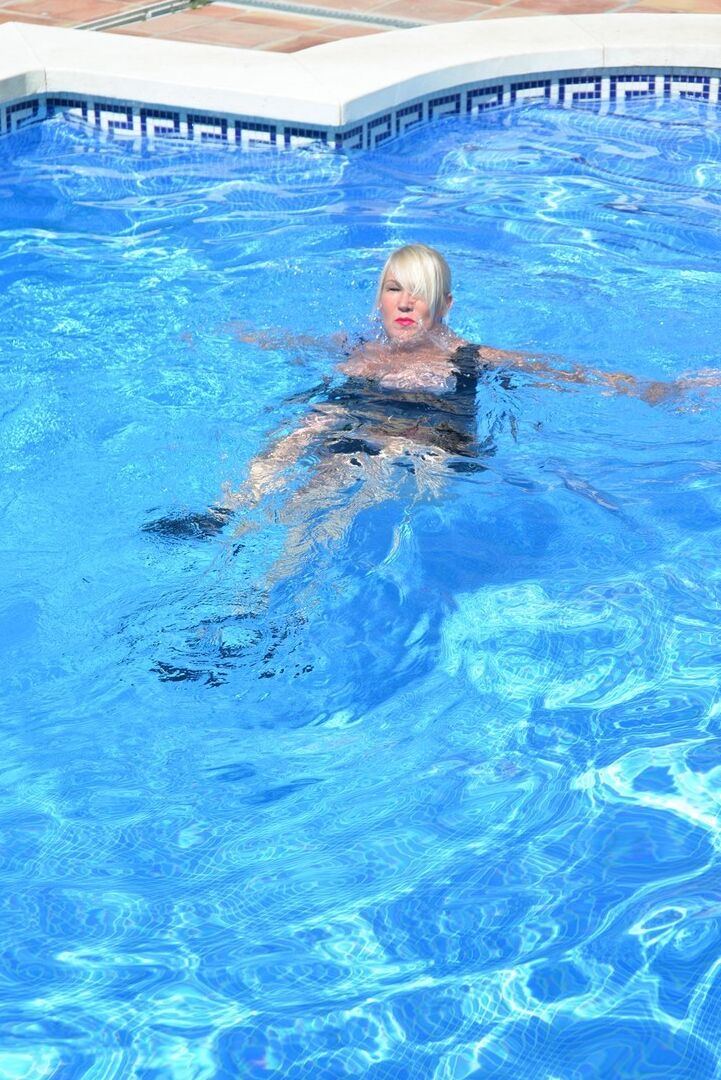 20P Thick blonde Melody displays her ample cleavage while fully clothed in a pool