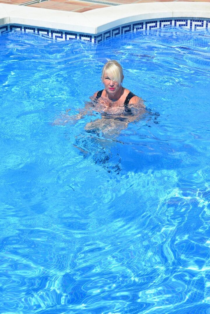 20P Thick blonde Melody displays her ample cleavage while fully clothed in a pool