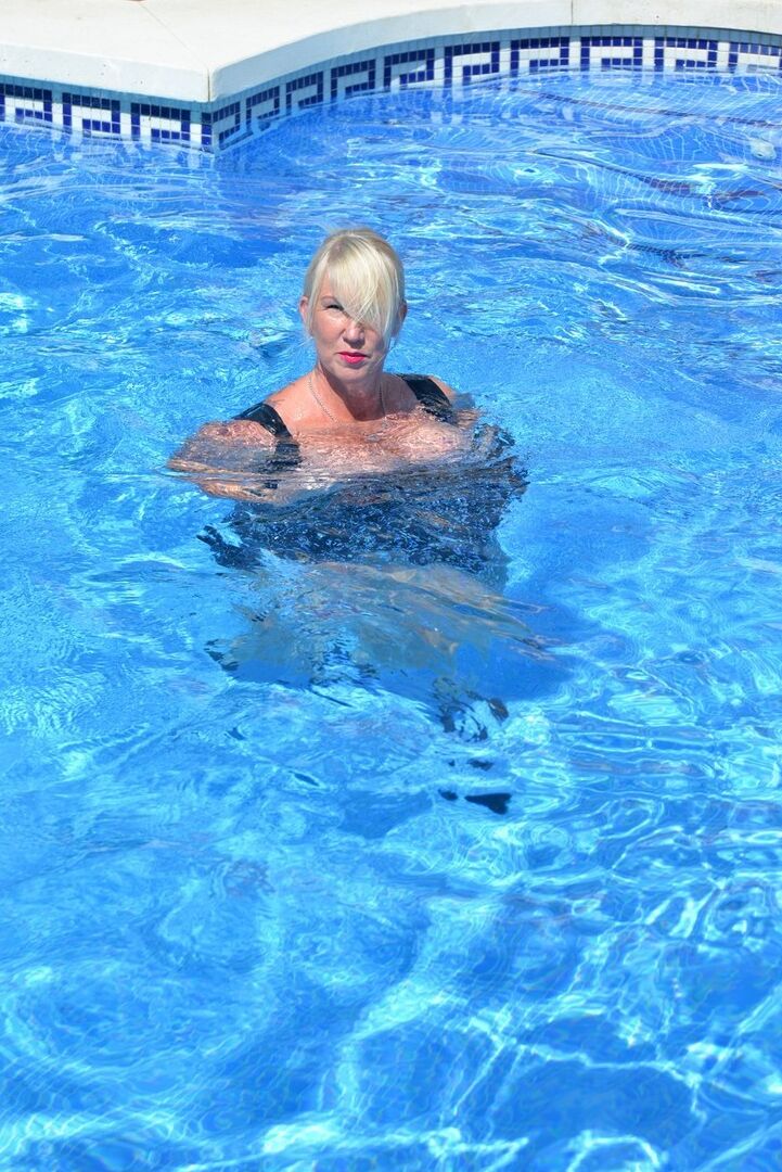 20P Thick blonde Melody displays her ample cleavage while fully clothed in a pool