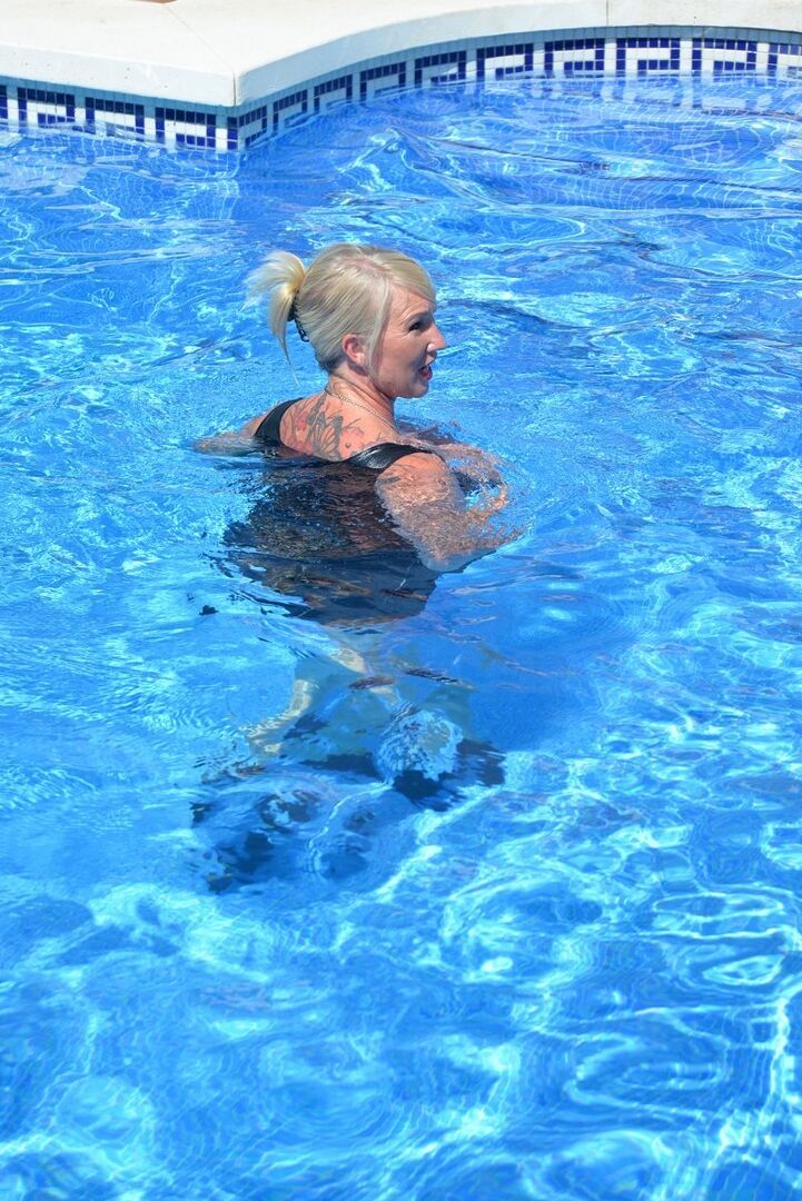 20P Thick blonde Melody displays her ample cleavage while fully clothed in a pool