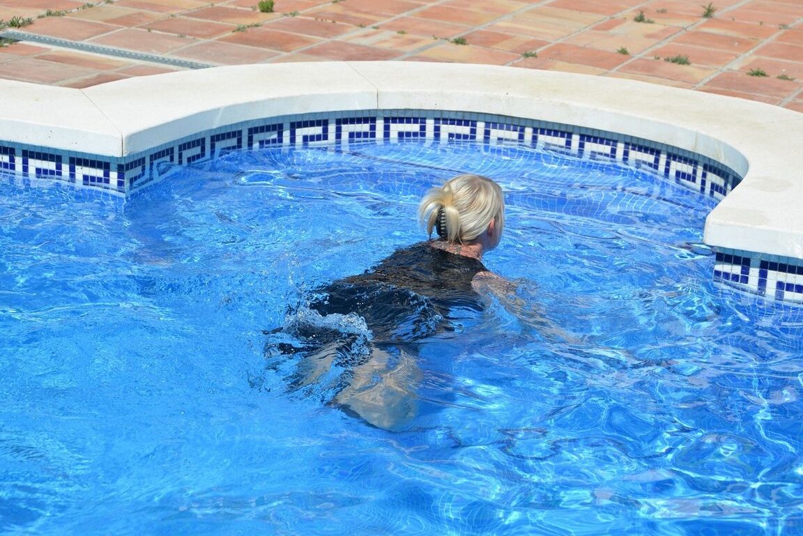 20P Thick blonde Melody displays her ample cleavage while fully clothed in a pool
