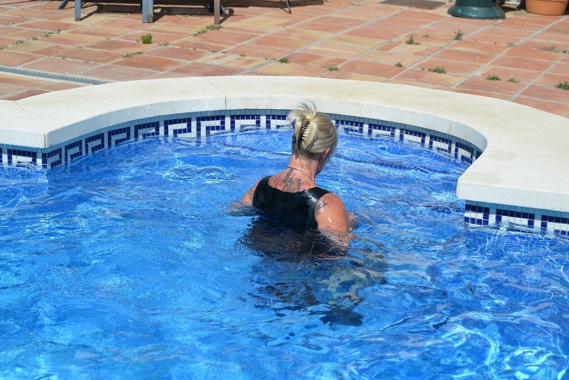 20P Thick blonde Melody displays her ample cleavage while fully clothed in a pool