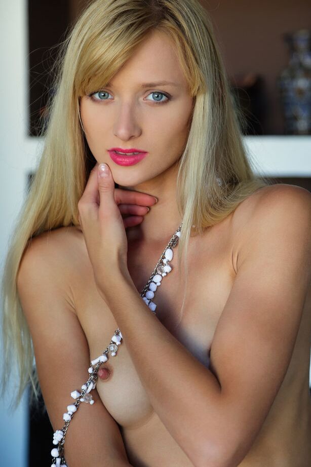 18P Erotic model Nika N drapes herself over the couch naked & barefoot in beads