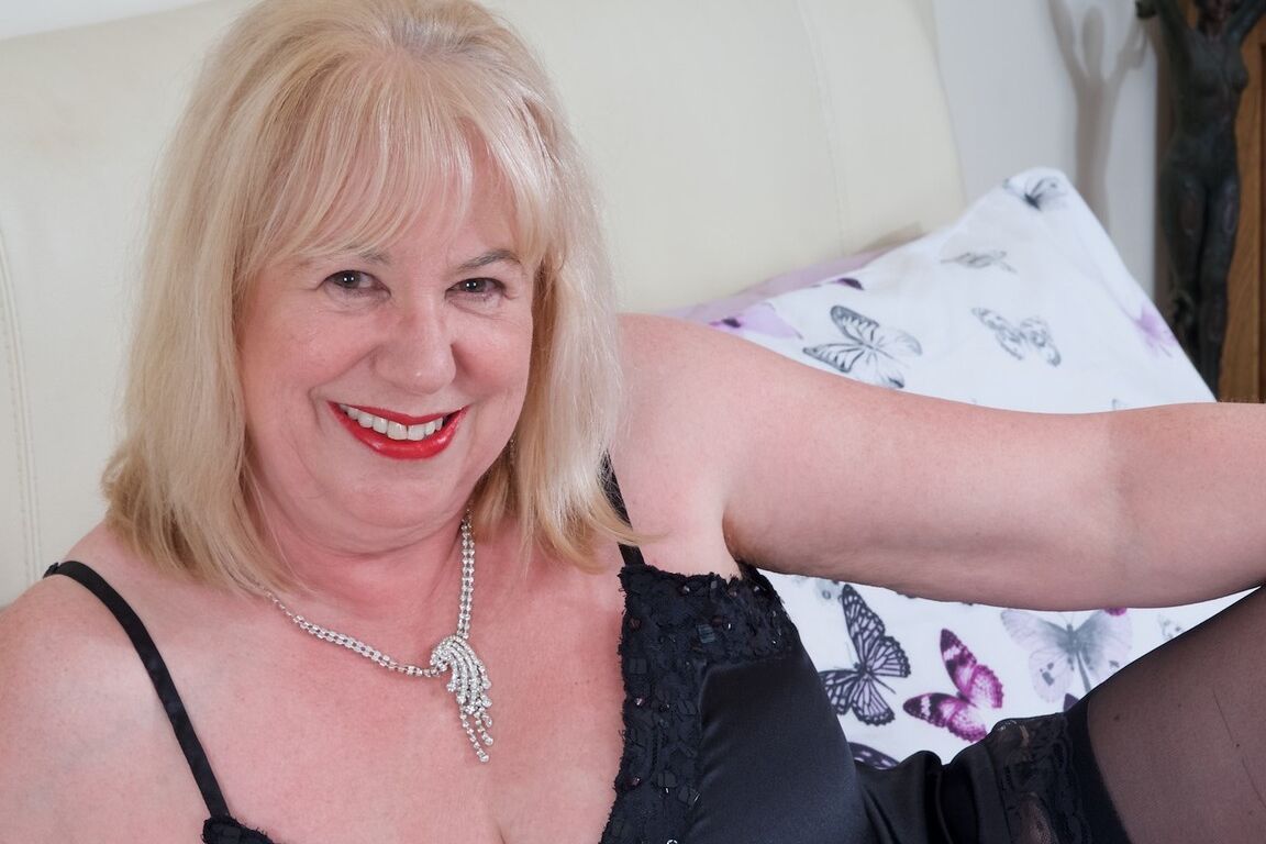 16P Mature UK fatty Speedy Bee doffs black negligee on a bed in back seam nylons