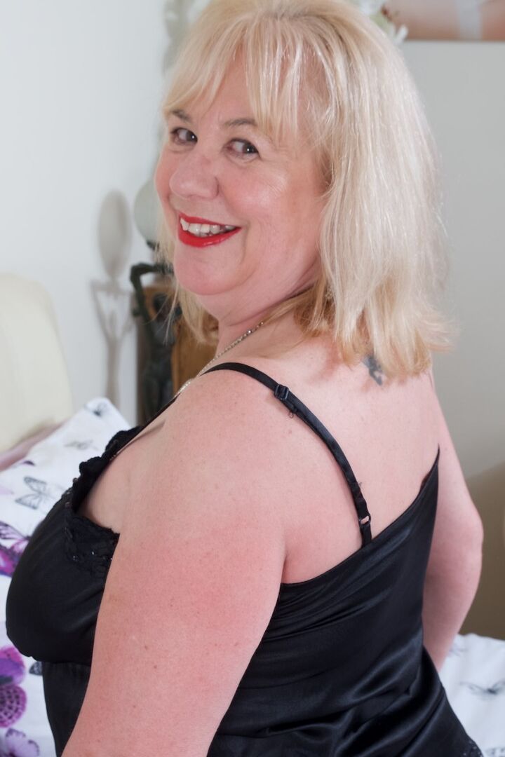 16P Mature UK fatty Speedy Bee doffs black negligee on a bed in back seam nylons