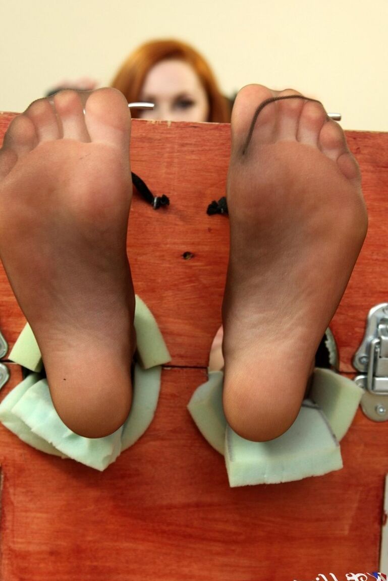 12P Natural redhead Sophie Nova removes her heels while her feet are in stocks