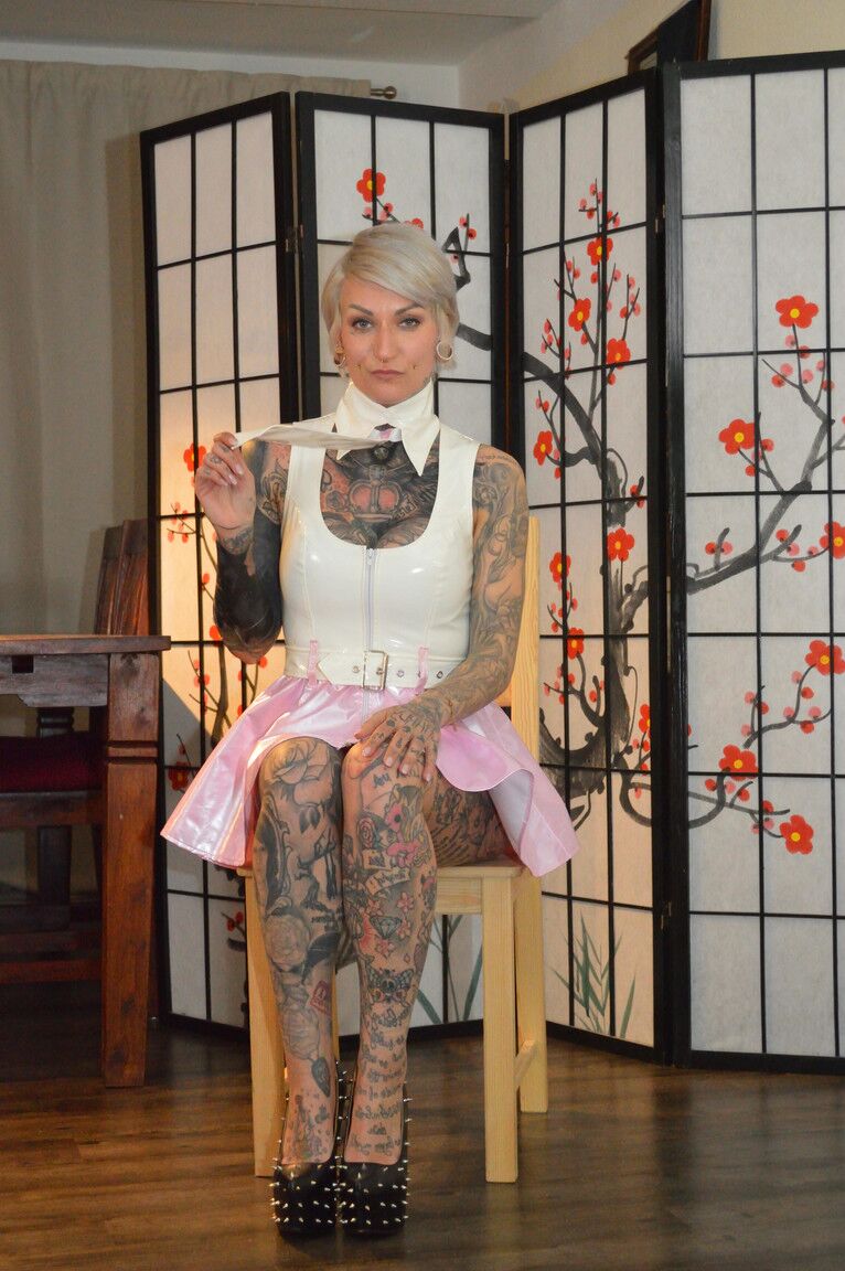 16P A loira platinada tatuada Miss Francine modela uma capa de chuva sobre um vestido de látex