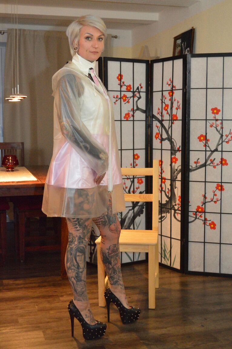 16P A loira platinada tatuada Miss Francine modela uma capa de chuva sobre um vestido de látex