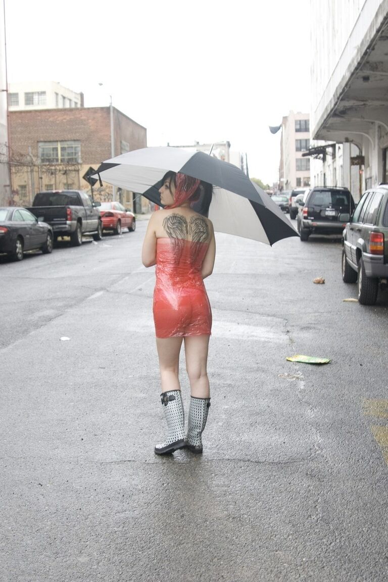 17P Adolescente totalmente mojada con piercings se quita el vestido de látex en un día lluvioso