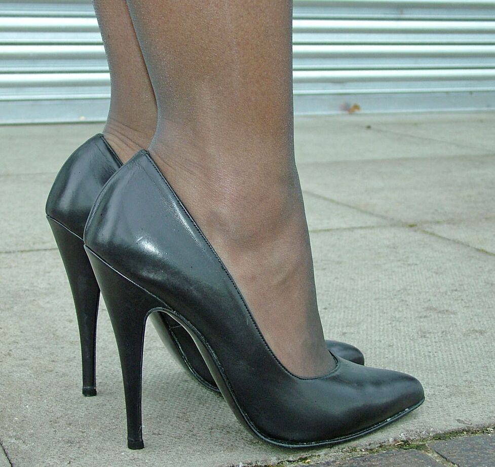 16P Modelo erótica em vestido preto exibe suas longas pernas em meia-calça transparente do lado de fora