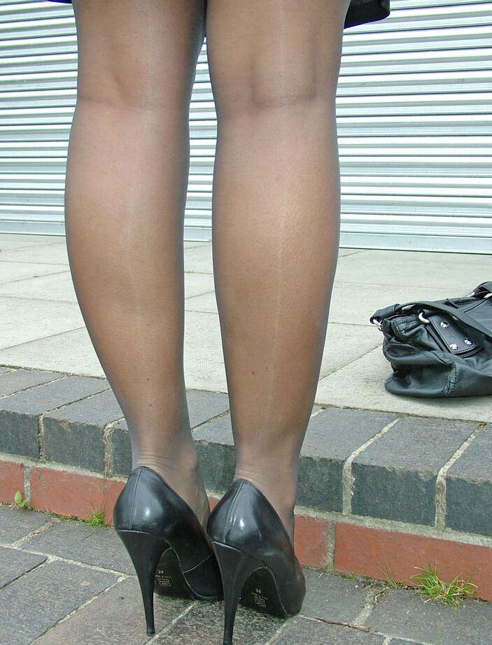 16P Modelo erótica em vestido preto exibe suas longas pernas em meia-calça transparente do lado de fora