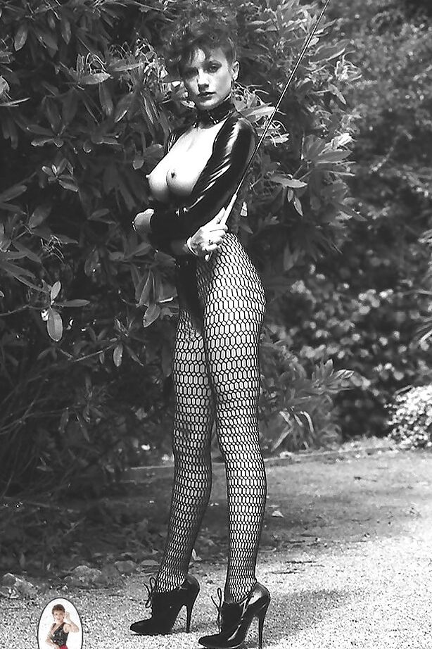 15P Señora de piernas largas con traje fetiche exponiendo sus tetas en un set de fotos vintage