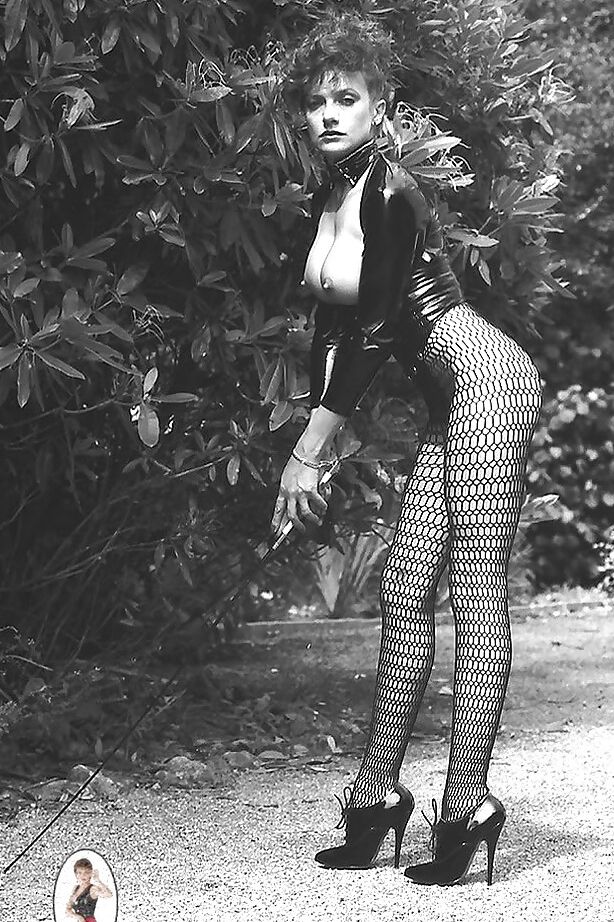 15P Señora de piernas largas con traje fetiche exponiendo sus tetas en un set de fotos vintage