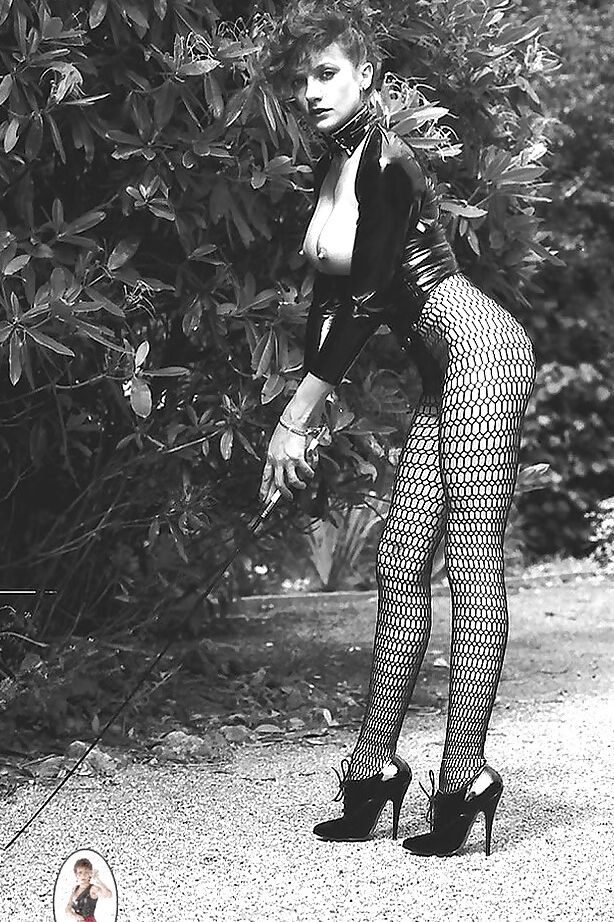 15P Señora de piernas largas con traje fetiche exponiendo sus tetas en un set de fotos vintage
