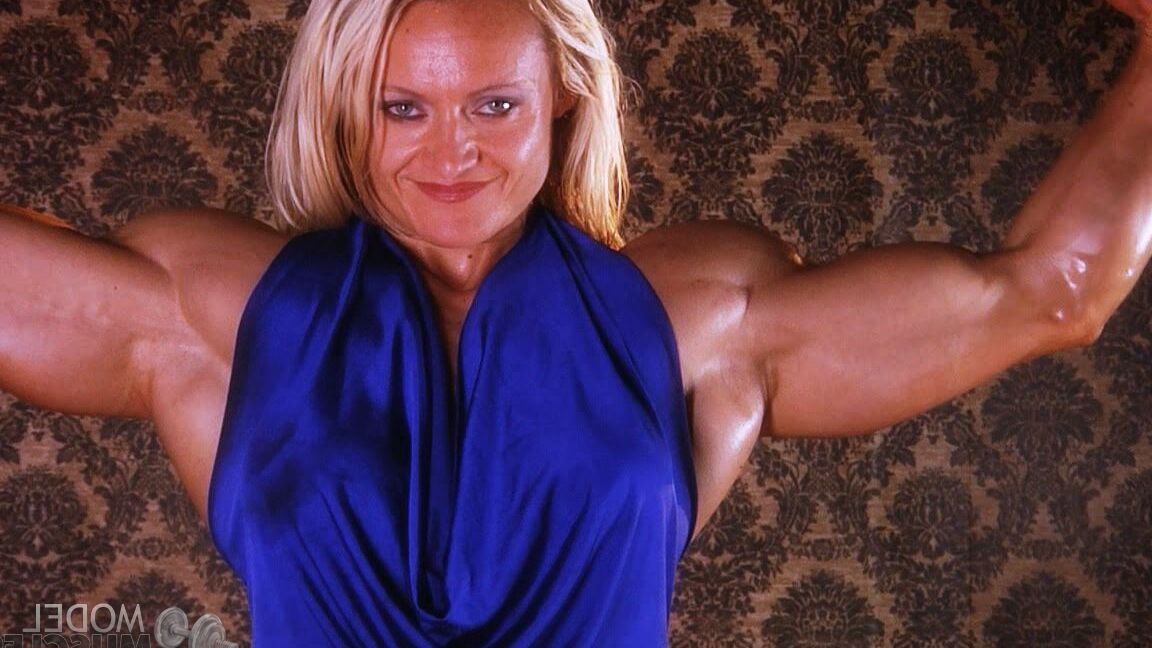 21P La culturista madura Brigita Brezovac flexionando sus grandes músculos con un vestido azul