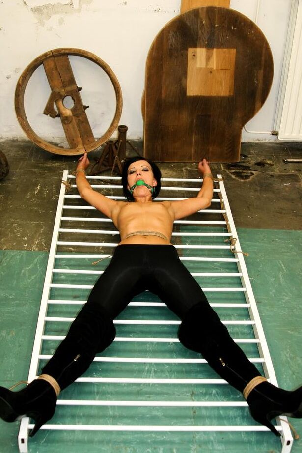 16P Dark haired female with tiny tits is ball gagged and tied to improvised rack