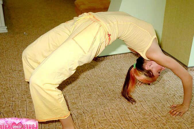 10P Flexible young girl stretches out on carpeted flooring while fully clothed
