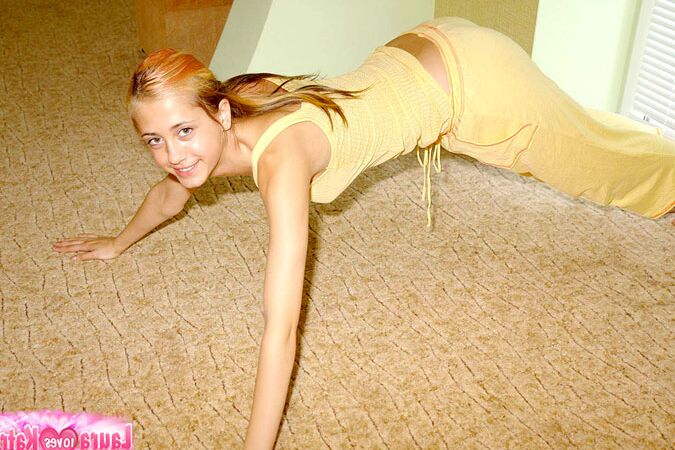 10P Flexible young girl stretches out on carpeted flooring while fully clothed