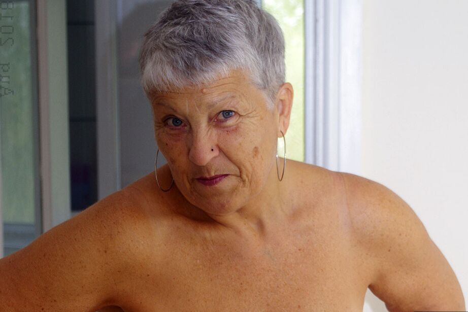 20P Short haired granny Savana uncups her large tits on a bed in mesh stockings