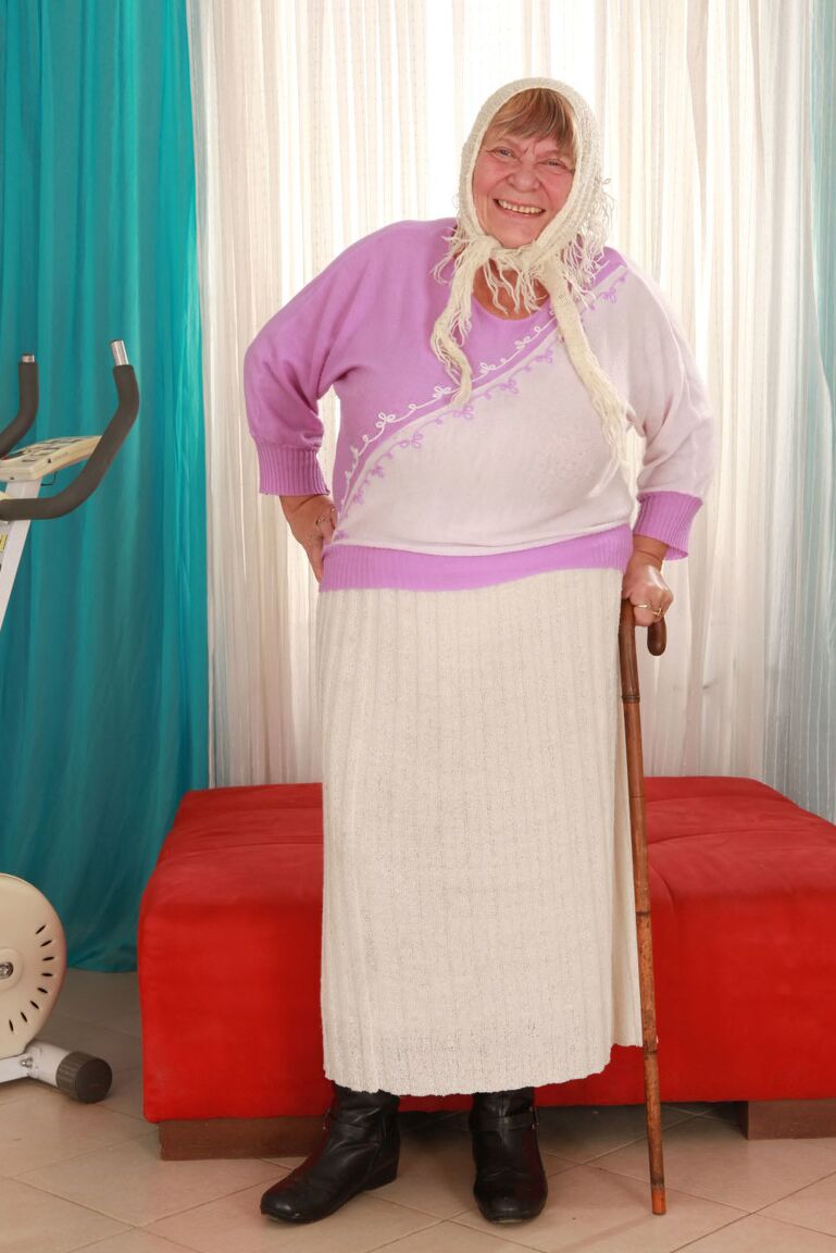 15P Old granny Sara G in skirt & boots sheds sweater to show huge tits in bra