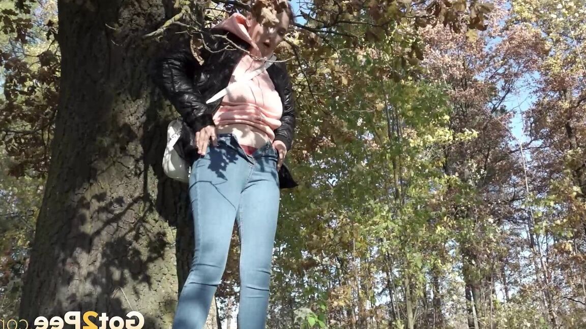 15P Kurz genommenes Mädel zieht ihre Jeans herunter, um neben einen Baum zu pinkeln